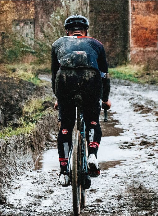 About Us Nomad Frontiers cyclist riding through mud