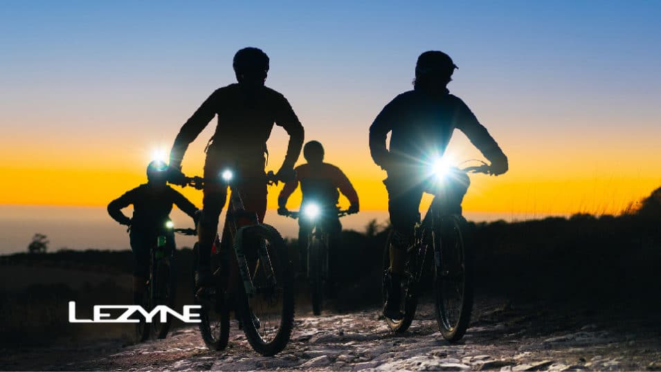 Cycling figures riding towards camera with Lezyne lights shining