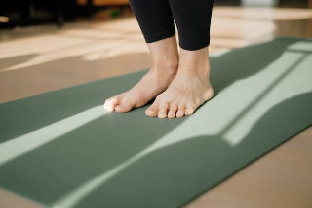 Person standing on a yoga mat to stretch