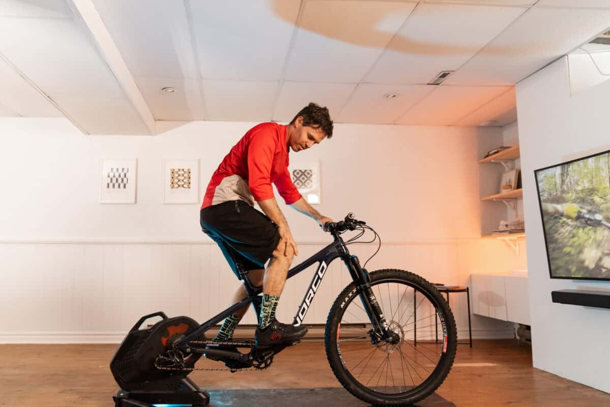 Man riding bike on indoor trainer rubbing his knee