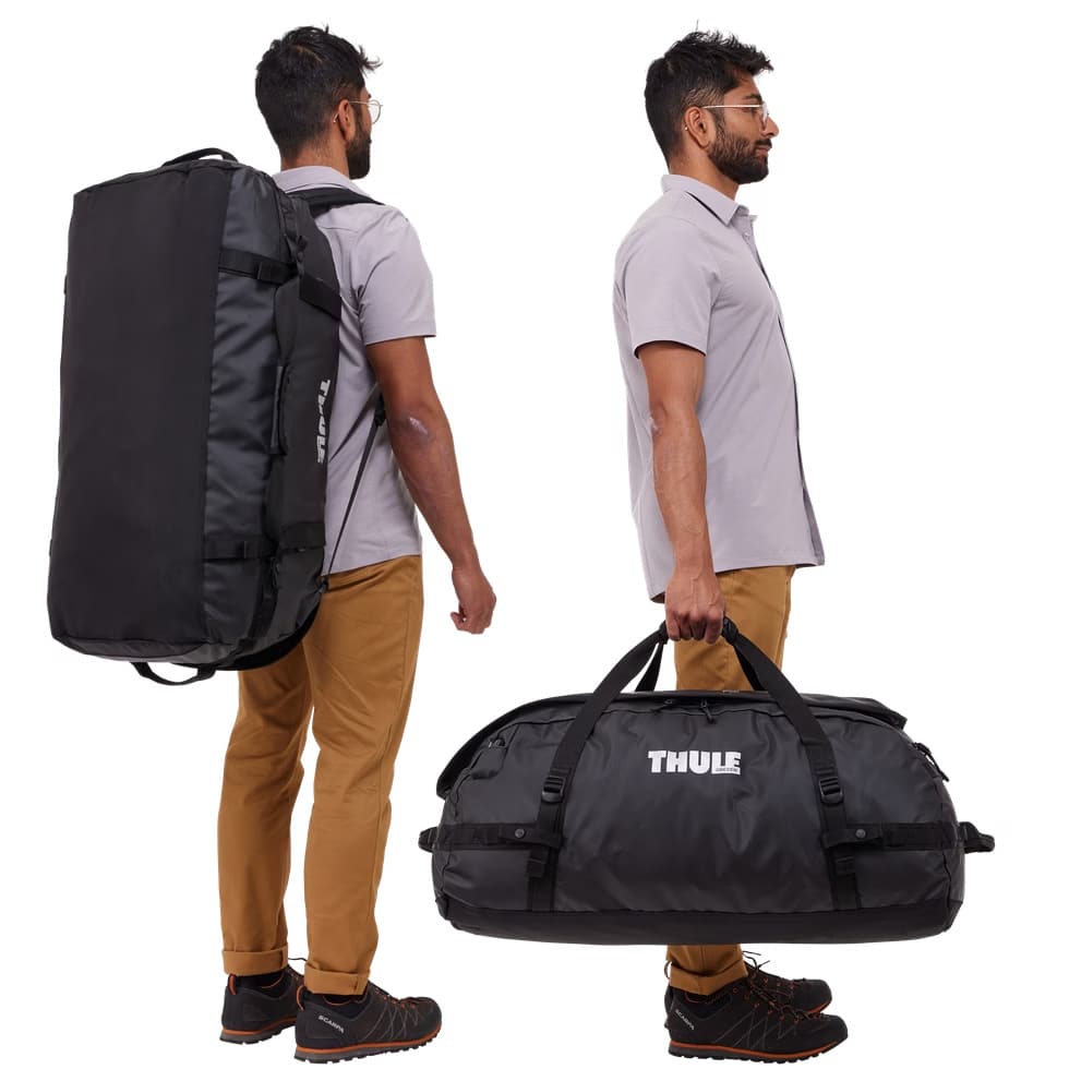 Thule Chasm Duffel 90L black carried by man in hand and on shoulder